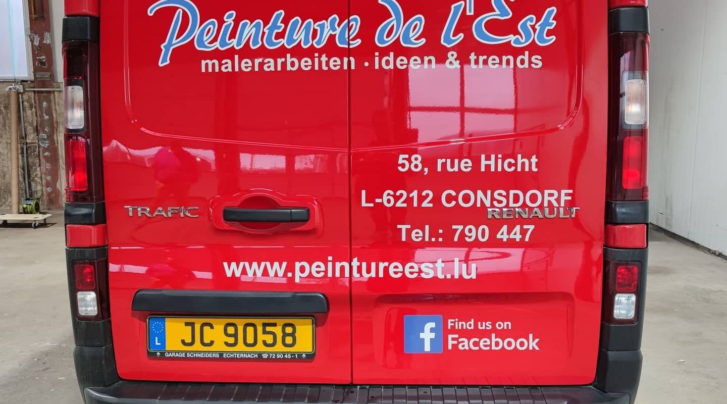 Beschriftete Hecktüren eines roten Firmentransporters